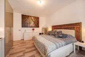 Une chambre à coucher comprenant un lit, une commode, un miroir, un tableau et une tête de lit décorative.