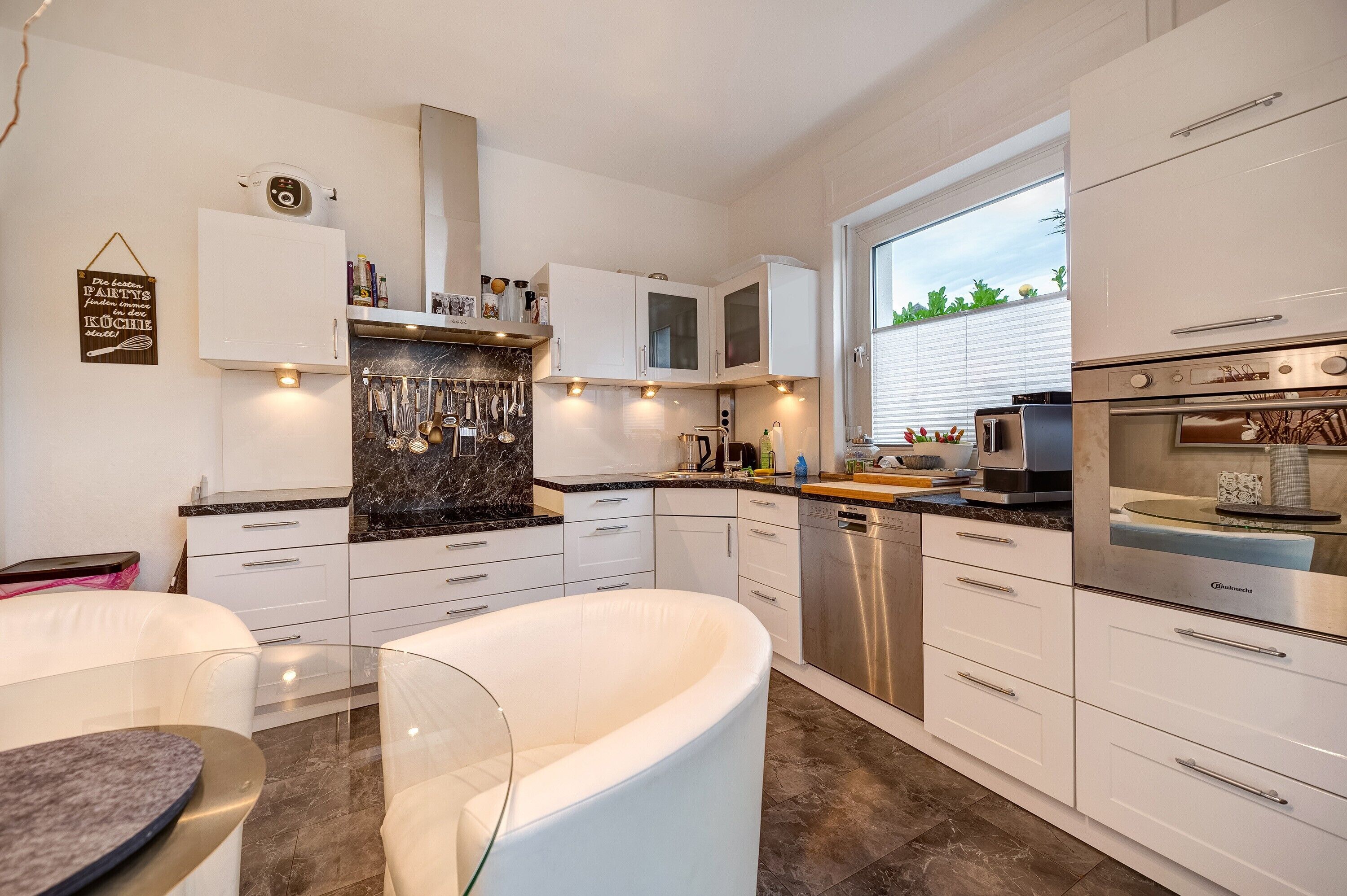 A modern kitchen with white cabinetry, a built-in oven, and a window providing natural light.