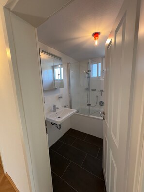 Une salle de bain moderne avec une douche à parois de verre, un lavabo blanc et un miroir.