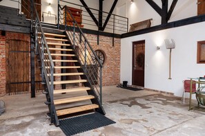 Un escalier avec des marches en bois et des rampes en métal, un mur de briques et une porte avec un cadre en bois.