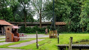 A rustic outdoor area with a wooden structure, a swing set, and a pond.