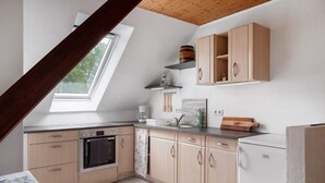 A kitchen with wooden cabinets, a built-in oven, a refrigerator, and a skylight.