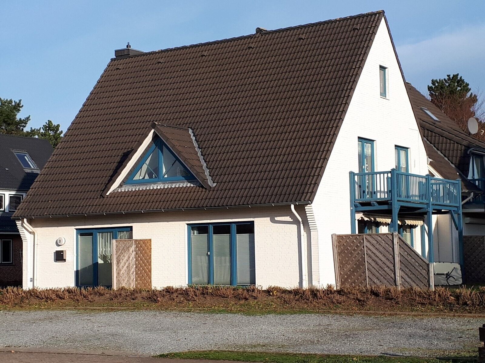 Ein zweistöckiges Haus mit geneigtem Dach, einem Balkon im zweiten Stock und einer kleinen Veranda.