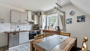Une cuisine moderne avec un coin repas, des meubles en bois et une fenêtre avec des rideaux.