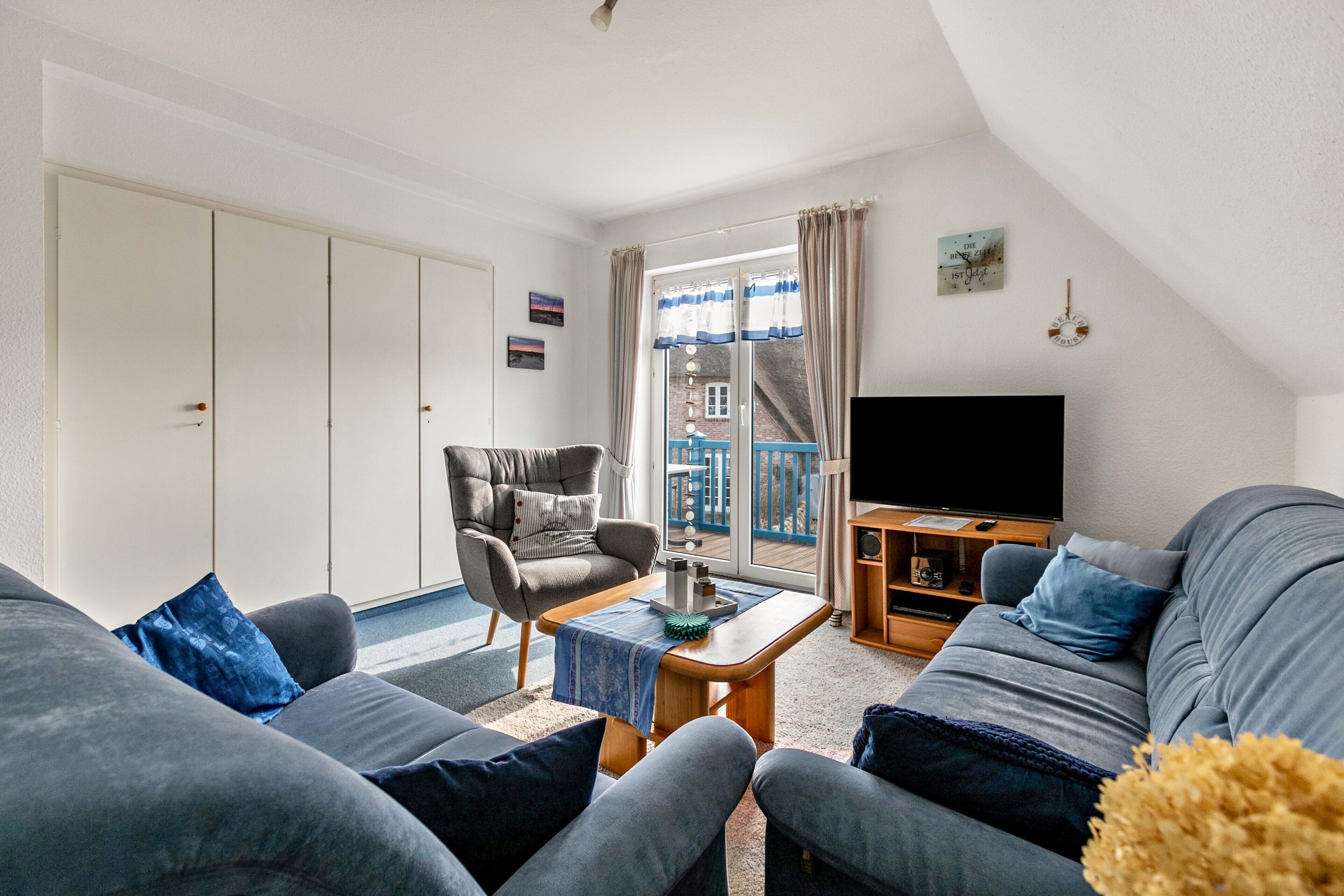 Ein Wohnzimmer mit einer Couch, einem Sessel und einem Fernseher.