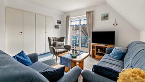 Un salon avec un canapé, un fauteuil et un téléviseur.