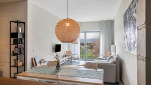A modern living room with a dining area, a large window, and a view of the outdoors.