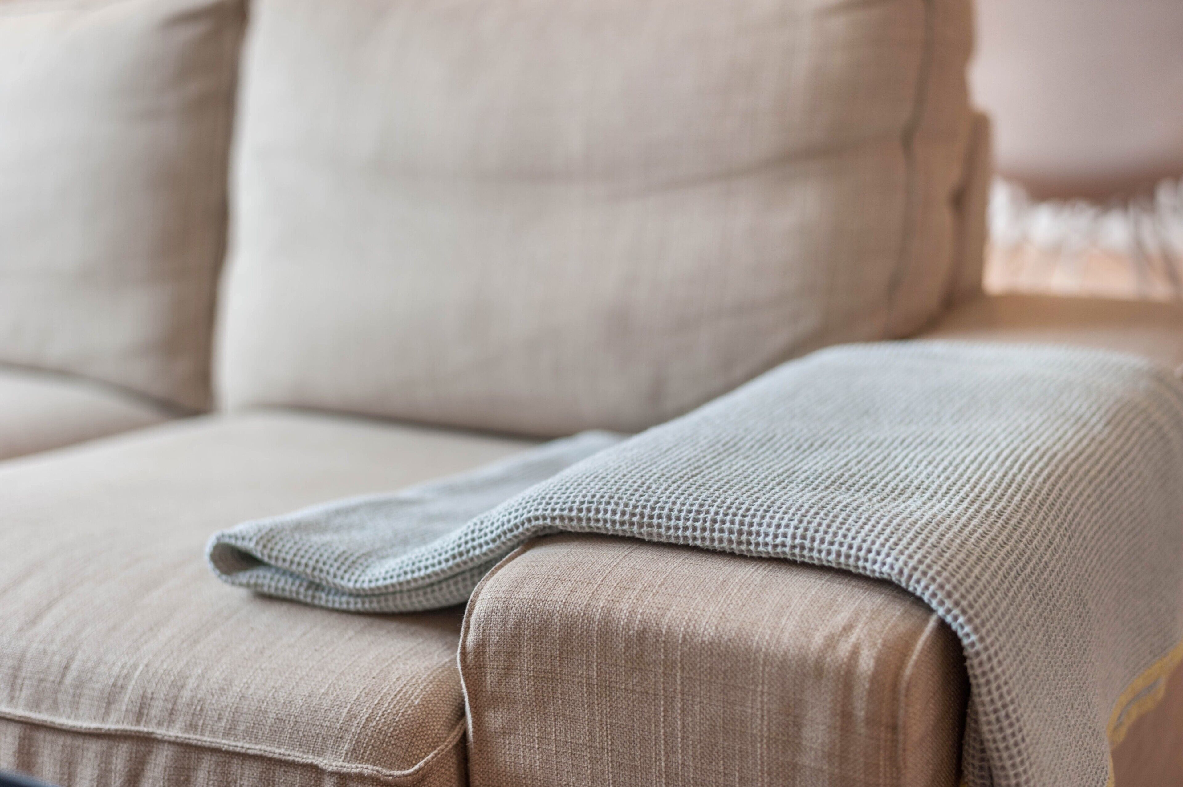 A beige sofa with a textured throw blanket.