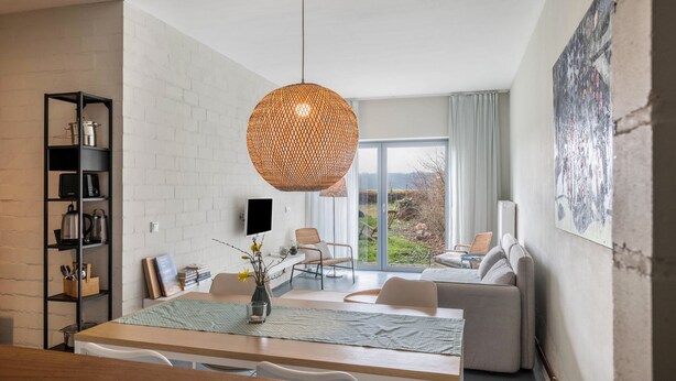 Een moderne woonkamer met een eethoek, een groot raam en uitzicht op de omgeving.