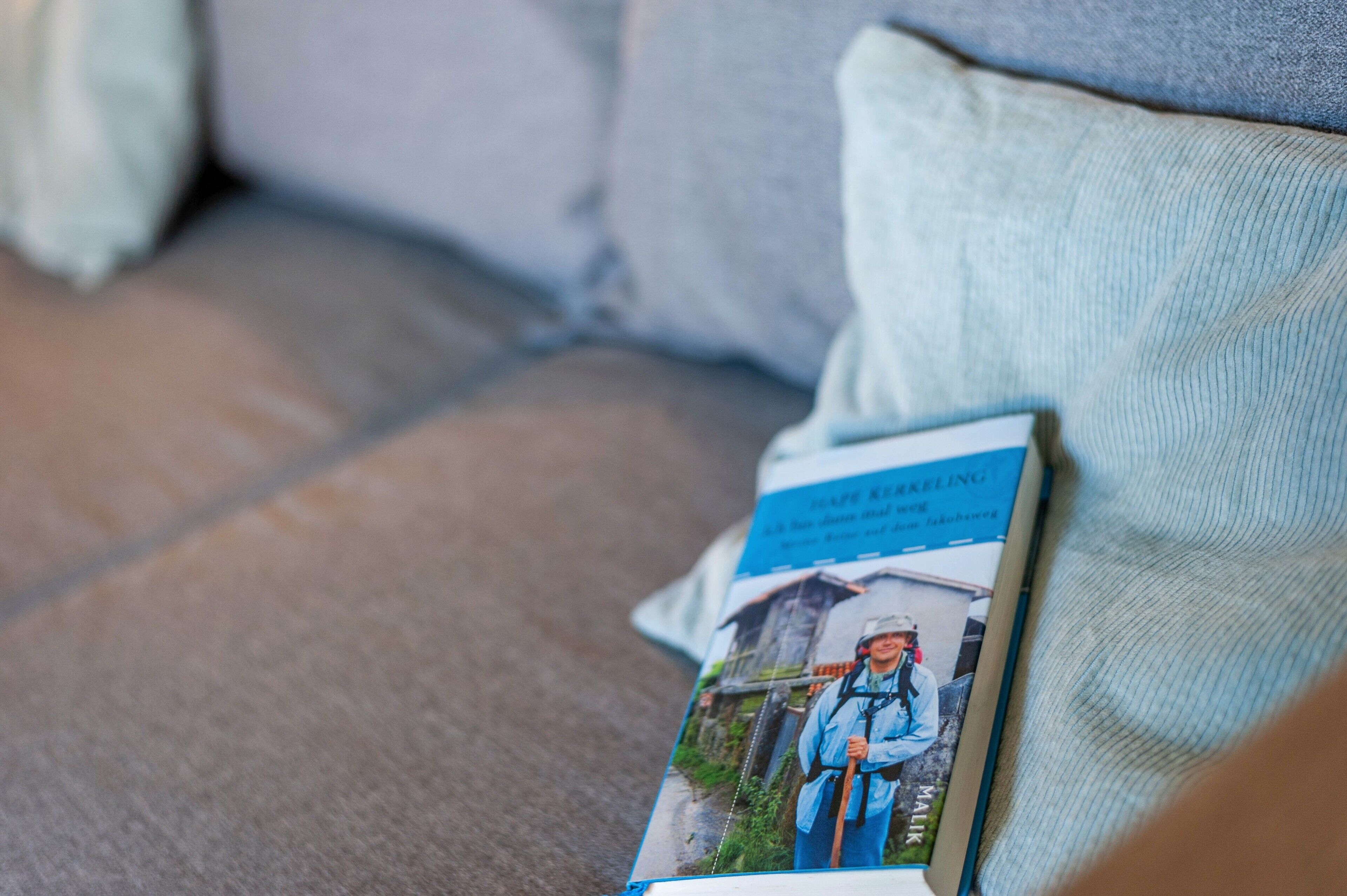 En tidning ligger på en soffa tillsammans med en kudde.