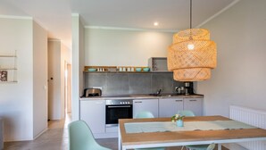 Une cuisine moderne avec des meubles gris, un plan de travail en bois et un luminaire suspendu.