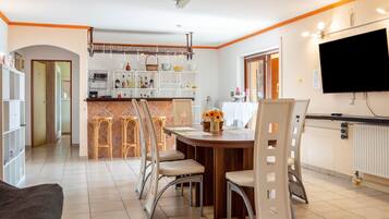 A modern kitchen with a dining area, bar stools, and a TV.