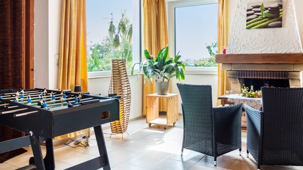 Ein Zimmer mit Kicker, Kamin und Blick ins Freie.