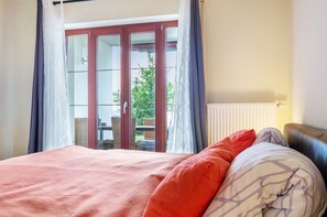 A bedroom with a bed, a window with curtains, and a view of the outdoors.