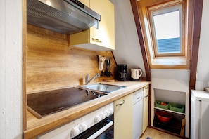 A compact kitchen with wooden countertops, a built-in oven, a sink, and a window with a view of a blue roof.