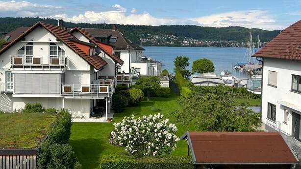 A residential area with houses, a green lawn, and a lake with boats. - Apartment 'Olivia' with Lake View, Shared Garden and Wi-Fi (Bodman-Ludwigshafen)