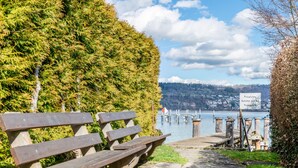 A bench, a pathway, and a sign near a body of water. - Apartment 'Olivia' with Lake View, Shared Garden and Wi-Fi (Bodman-Ludwigshafen)