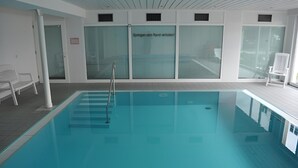 An indoor swimming pool with a glass wall, a pool ladder, and a sign in German. - Apartment 'Olivia' with Lake View, Shared Garden and Wi-Fi (Bodman-Ludwigshafen)