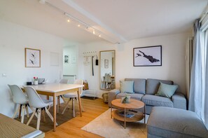 Ein modernes Wohnzimmer mit Essbereich, grauem Sofa und einem großen gerahmten Kunstwerk an der Wand.
