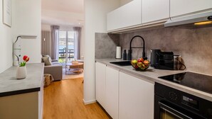 A modern kitchen with white cabinets, a black stove, and a fruit bowl on the counter. - Apartment 'Olivia' with Lake View, Shared Garden and Wi-Fi (Bodman-Ludwigshafen)