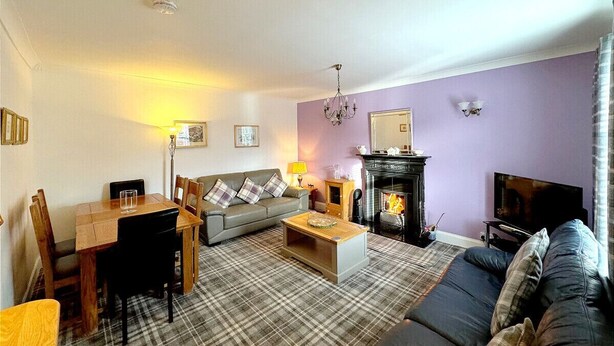 A living room with a fireplace, sofa, and dining area. - Ameliafield Cottage in Prestwick (Prestwick)