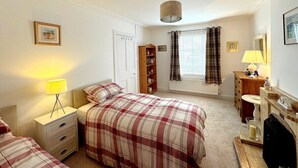 A bedroom with a bed, bedside tables, a wardrobe, a radiator, and a window with curtains. - Ameliafield Cottage in Prestwick (Prestwick)