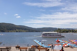 A lakeside view with a boat docked, benches, and a clear sky.