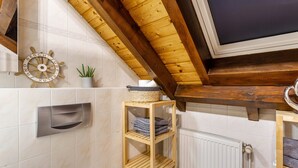 A bathroom with a wooden ceiling, a towel rack, a shelf with towels, a potted plant, and a ship's wheel decoration. - Apartment 'Ferienwohnung Rinke' with Mountain View and Balcony (Schmallenberg)