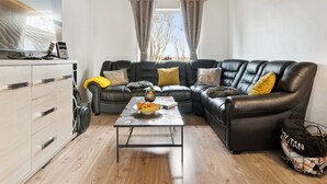 A modern living room with a sectional sofa, a coffee table, and a flat-screen TV on a wooden cabinet. - "Elara" - 300m from the sea by Interhome (Thyholm)