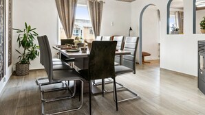 A modern dining area with a wooden ceiling, a dining table with chairs, and a view of buildings outside. - "Elara" - 300m from the sea by Interhome (Thyholm)