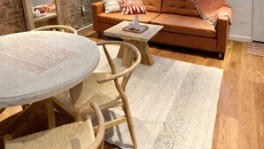 Una sala de estar con pared de ladrillo, un sofá, una mesa de centro y una mesa de comedor con sillas.