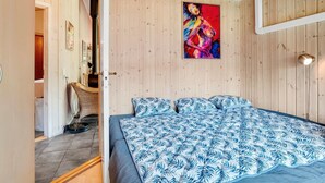 Een slaapkamer met een bed, een schilderij en een houten plafond.