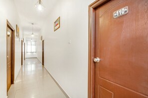 A hallway with a wooden door labeled "110" and a light fixture above it. - iROOMZ Hotel Royal Hill Park (Hyderabad)
