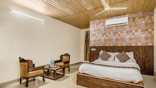 A bedroom with a bed, a wooden ceiling, an air conditioner, and a patterned wall. - iROOMZ Hotel Royal Hill Park (Hyderabad)