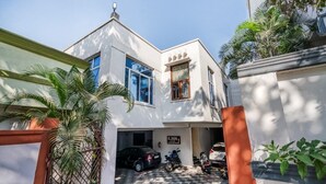 A two-story building with a garage, parked vehicles, and a gated entrance. - iROOMZ Hotel Royal Hill Park (Hyderabad)
