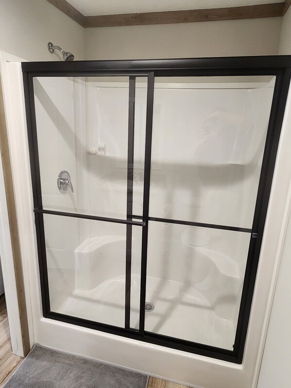 A glass-enclosed shower with a black frame, a visible drain, and a showerhead. - Cozy cottage w/1 bedroom, WiFi, AC in tranquil Springville close to boat ramps (Springville)