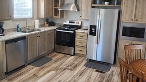 A modern kitchen with wooden cabinets, stainless steel appliances, and a herringbone wood floor. - Cozy cottage w/1 bedroom, WiFi, AC in tranquil Springville close to boat ramps (Springville)