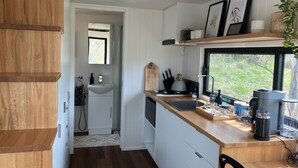 Eine moderne Küche mit weißen Schränken, einer Holzarbeitsplatte und einem Fenster mit Blick auf Grünflächen.