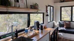 Eine moderne Küche mit großen Fenstern, einer Holz Arbeitsplatte und verschiedenen Küchengeräten.