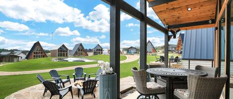 A patio area with outdoor seating, a view of a golf course, and a large building in the background.