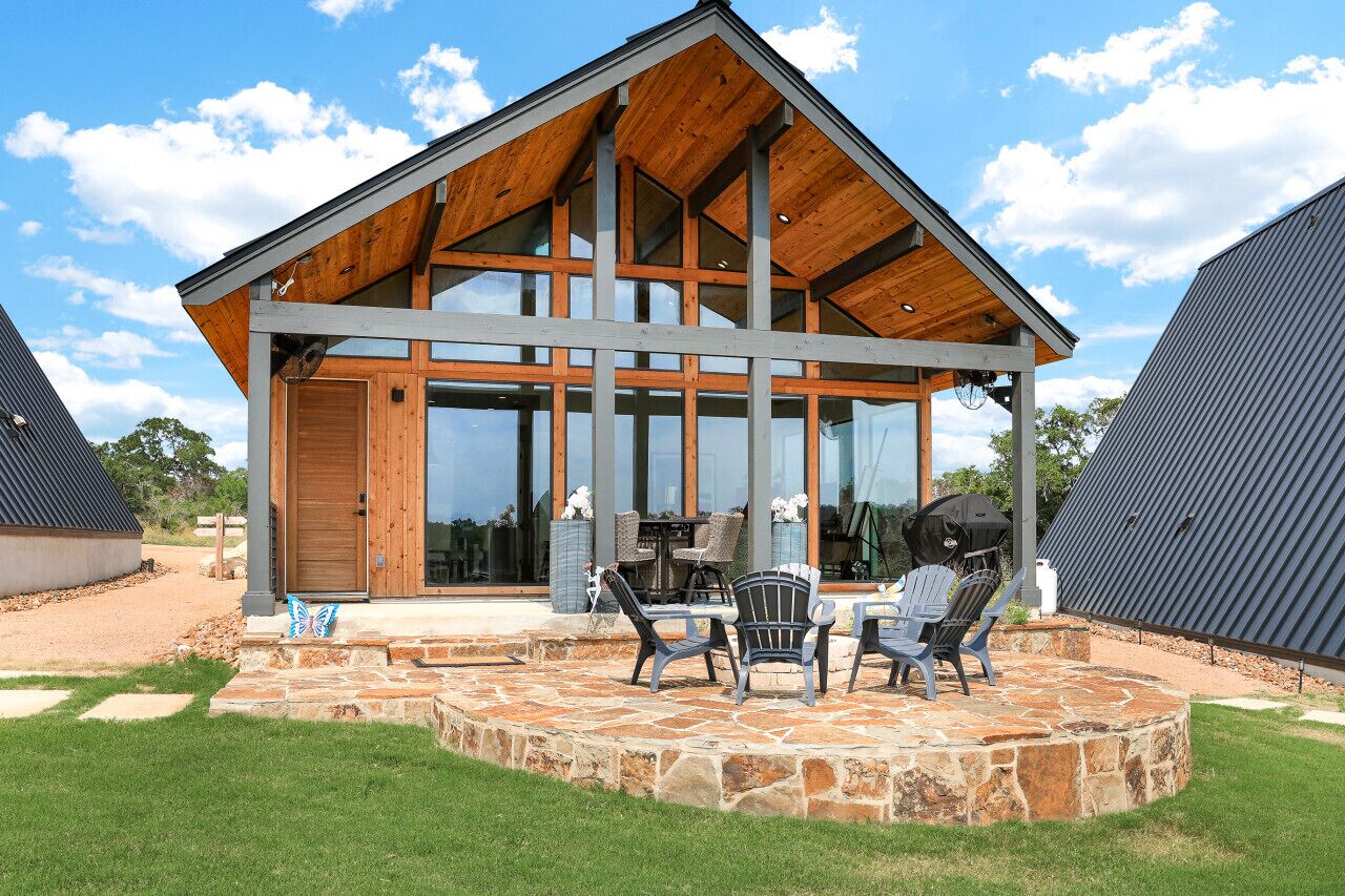 A modern house with a large deck, outdoor seating, and a grill area.