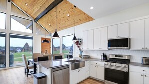 Una cocina moderna con armarios blancos, electrodomésticos de acero inoxidable y techo de madera.