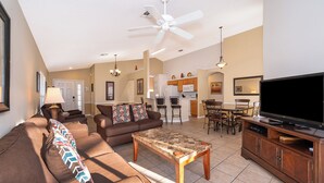 A spacious living room with a sofa, coffee table, and TV. There is a kitchen area with a microwave and refrigerator. - New! Lesa's Disney Vacation Home (Davenport)