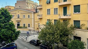 A multi-story residential building with balconies, a street with parked cars, and a pedestrian crossing. - Scent of Sorrento in Rome  (Roma)