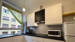 A compact kitchen with white cabinets, a microwave, and a built-in oven. - Scent of Sorrento in Rome  (Roma)