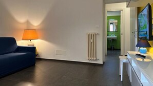 A modern living room with a sofa, a lamp, a radiator, and a television. - Scent of Sorrento in Rome  (Roma)