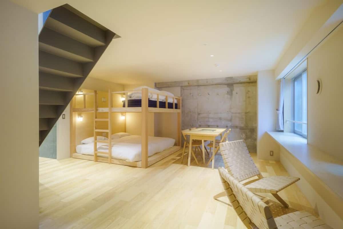 A compact room with a bunk bed, a small table, a chair, and a window.