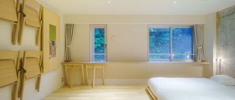 A bedroom with a bed, wooden chairs, a desk, and windows with curtains.