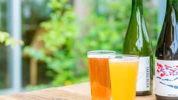 Two glasses of beer and two bottles on a wooden table with a blurred green background.