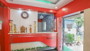 A reception area with a red and white color scheme, a clock, and decorative vases. - Hotel Orbit Digha (Kanthi)